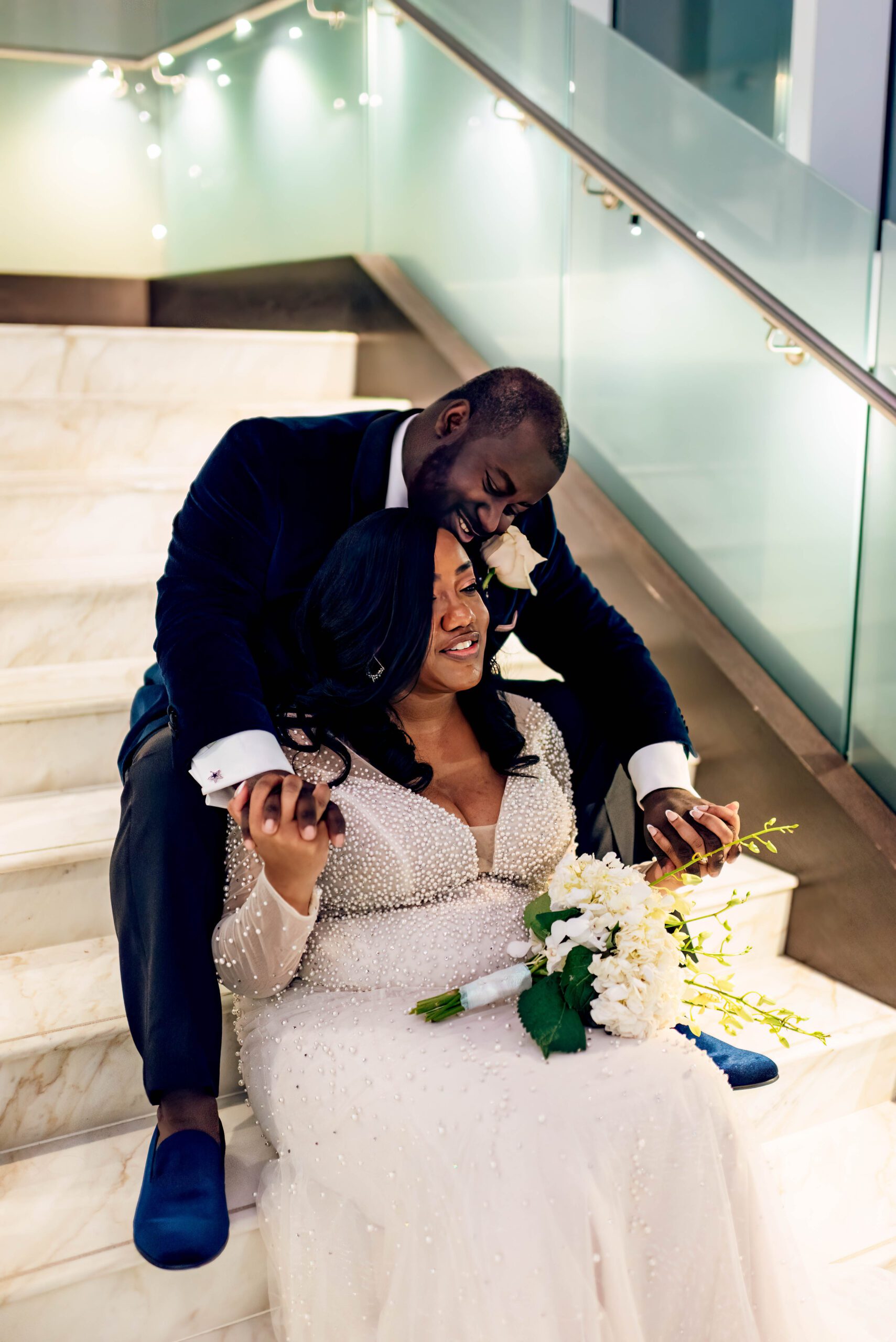 Bride and groom sitting on stairs in Kimpton Tryon Park hotel